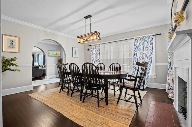 dining space featuring a brick fireplace, crown molding, and dark hardwood / wood-style floors