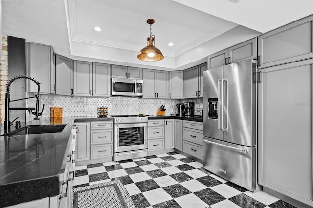 kitchen featuring high end appliances, sink, gray cabinetry, and a tray ceiling