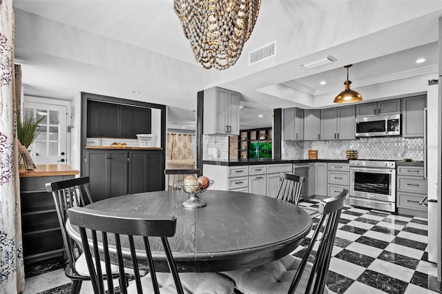 dining area with crown molding, a raised ceiling, and a chandelier