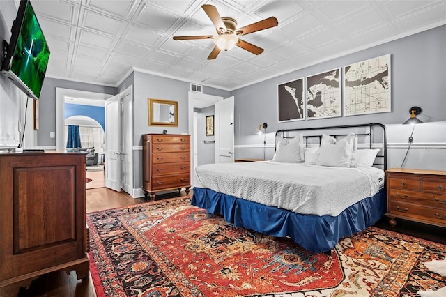 bedroom featuring crown molding, ensuite bath, ceiling fan, and light wood-type flooring