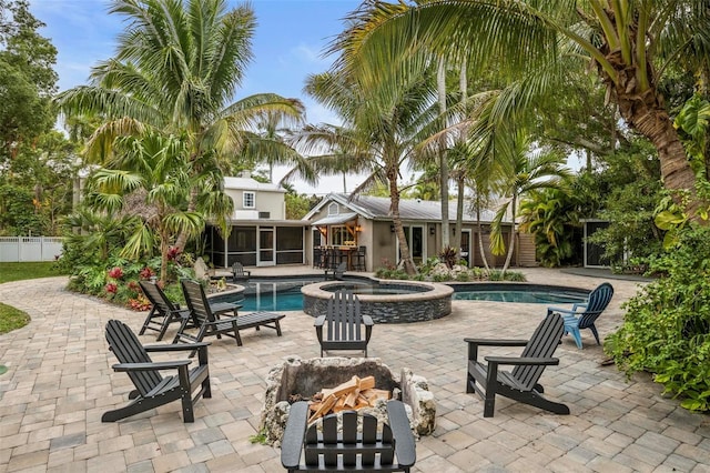 view of pool featuring an in ground hot tub, an outdoor fire pit, a patio, and a sunroom