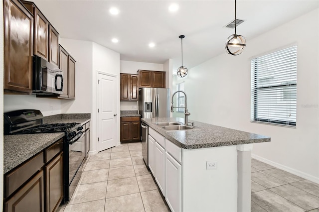 kitchen featuring pendant lighting, sink, dark brown cabinets, black appliances, and a center island with sink