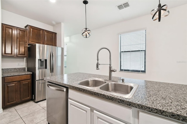 kitchen with sink, light tile patterned floors, appliances with stainless steel finishes, hanging light fixtures, and dark brown cabinets