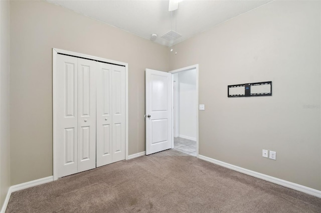 unfurnished bedroom featuring ceiling fan, light colored carpet, and a closet