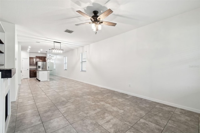 unfurnished living room featuring light tile patterned flooring and ceiling fan with notable chandelier