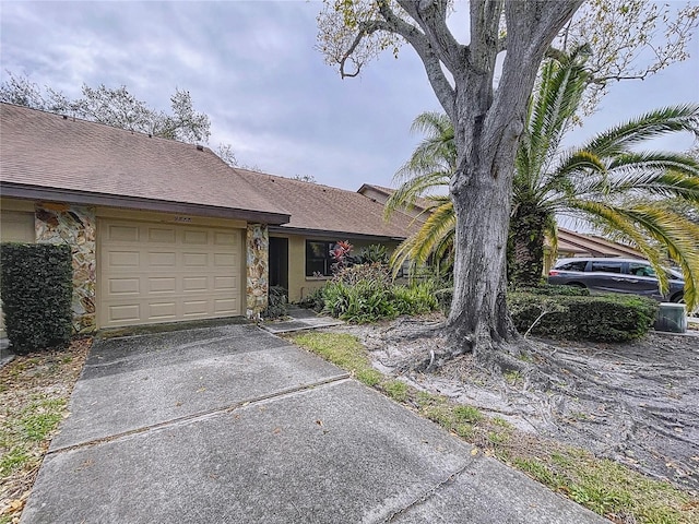 single story home with a garage, a shingled roof, concrete driveway, stone siding, and stucco siding