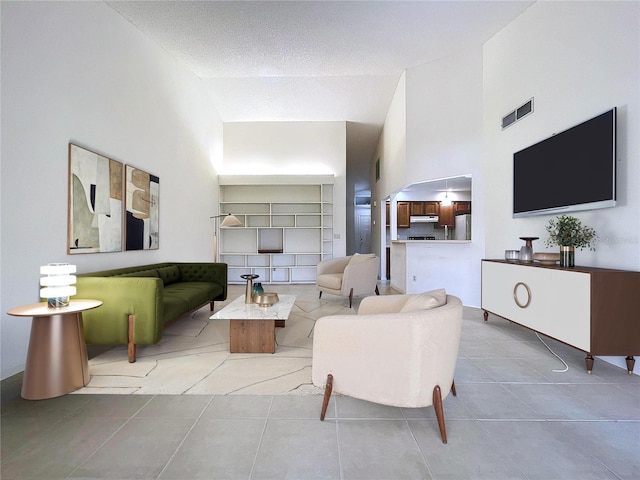 living room with high vaulted ceiling, visible vents, and tile patterned floors