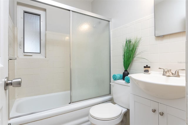 full bathroom featuring combined bath / shower with glass door, tasteful backsplash, tile walls, vanity, and toilet