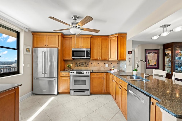 kitchen with sink, decorative backsplash, dark stone counters, light tile patterned floors, and stainless steel appliances