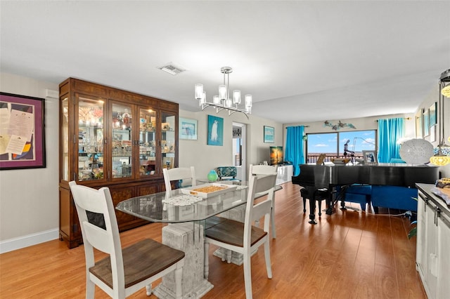 dining area with light hardwood / wood-style floors and a notable chandelier