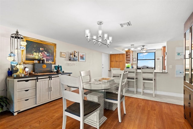 dining area with ceiling fan with notable chandelier and light hardwood / wood-style floors