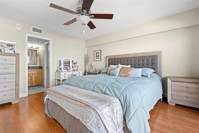 bedroom with hardwood / wood-style flooring, ceiling fan, and ensuite bath