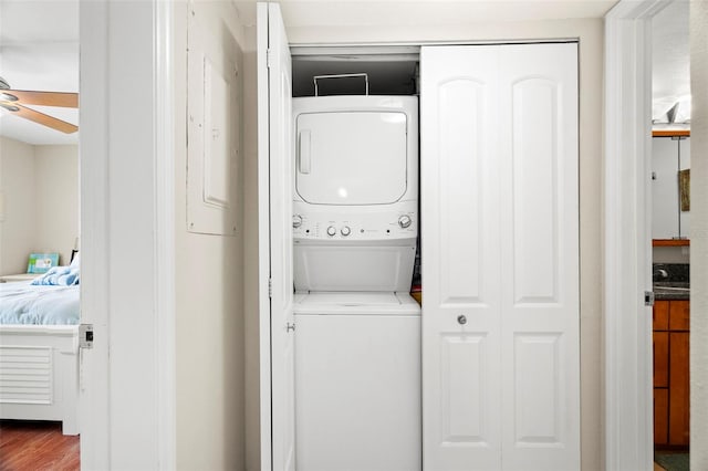 laundry room featuring hardwood / wood-style flooring, ceiling fan, and stacked washer / dryer