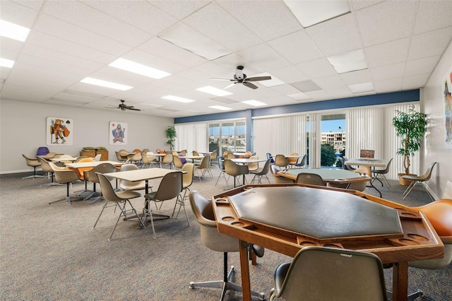 carpeted dining area with a drop ceiling and ceiling fan