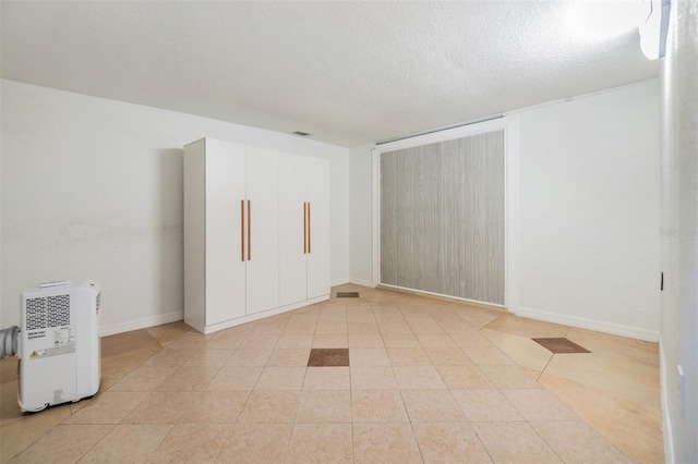 empty room with light tile patterned floors and a textured ceiling