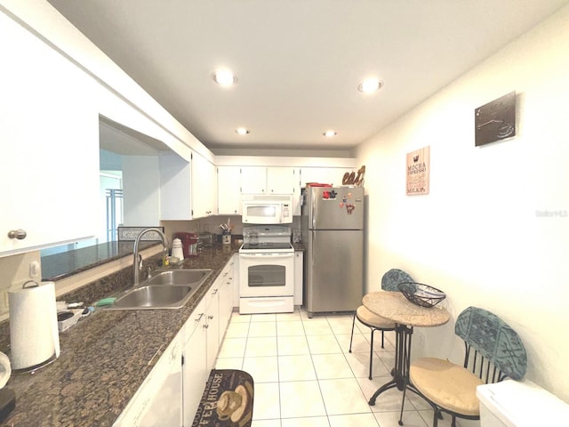 kitchen with sink, white appliances, white cabinetry, dark stone countertops, and light tile patterned flooring