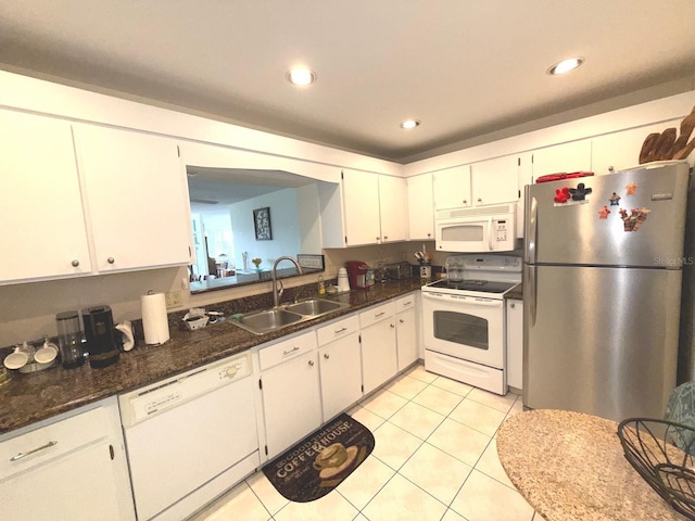 kitchen featuring sink, white appliances, dark stone countertops, white cabinets, and light tile patterned flooring