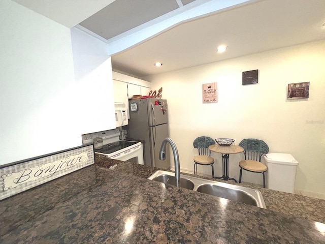 kitchen featuring sink, white cabinets, dark stone counters, kitchen peninsula, and white appliances