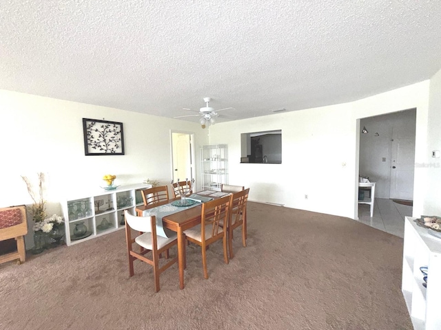 carpeted dining area featuring a textured ceiling and ceiling fan