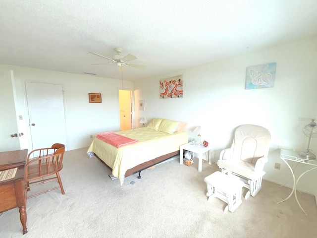 carpeted bedroom featuring ceiling fan and a textured ceiling