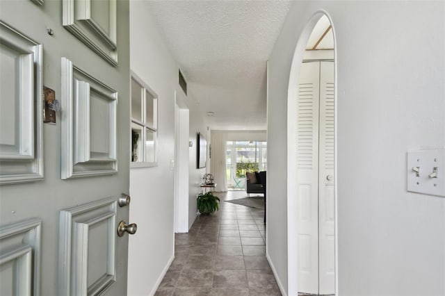 hall with tile patterned floors and a textured ceiling