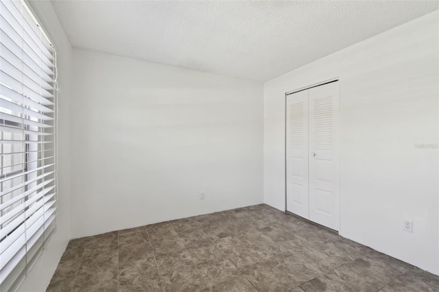 unfurnished bedroom with a textured ceiling and a closet