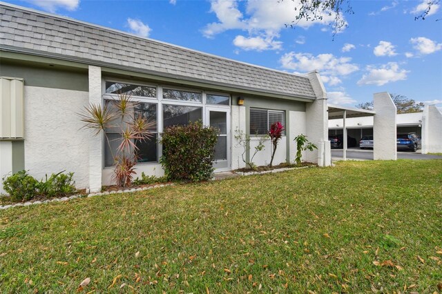 4732 Lake Blvd Unit A, Clearwater, FL 33762 - back of property with stucco siding, mansard roof, an attached carport, a shingled roof, and a yard