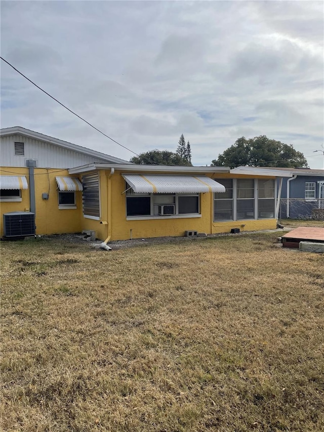 view of front of home with a sunroom, a front lawn, and central air condition unit