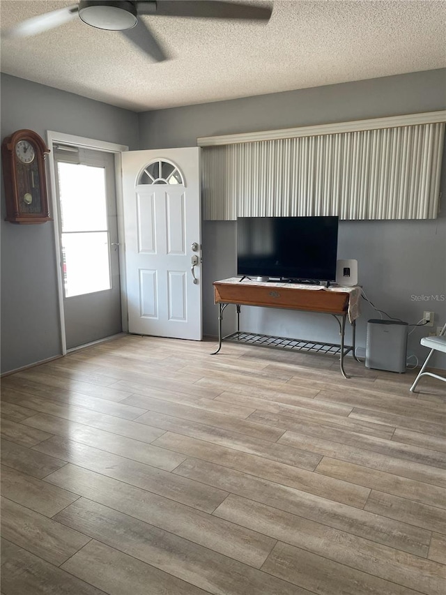 interior space featuring ceiling fan, light hardwood / wood-style floors, and a textured ceiling