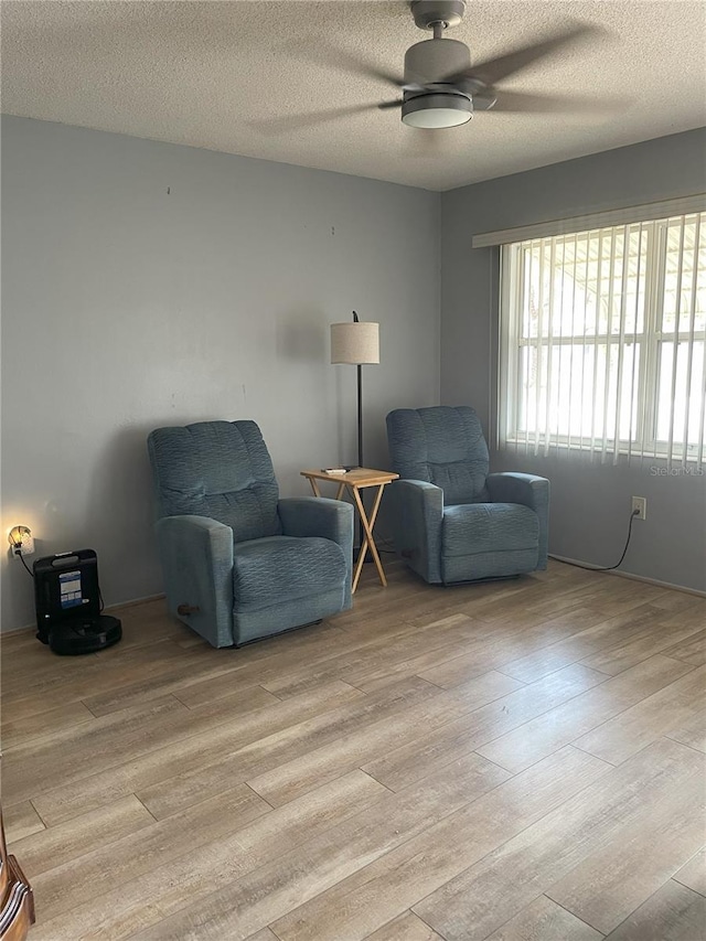 living area featuring a textured ceiling, ceiling fan, and light wood-type flooring