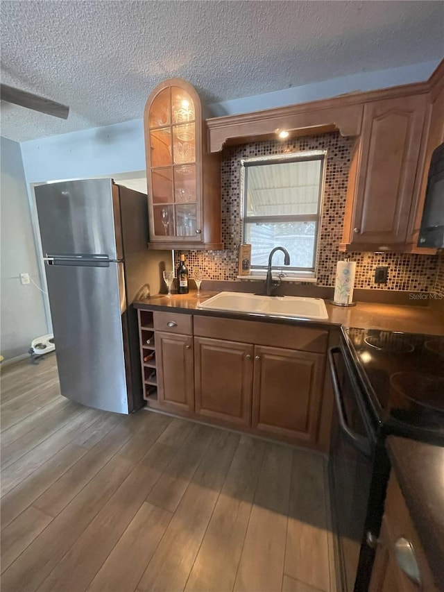 kitchen with light wood-type flooring, backsplash, sink, and black appliances