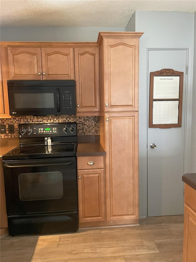 kitchen with backsplash, light hardwood / wood-style flooring, black appliances, and a textured ceiling