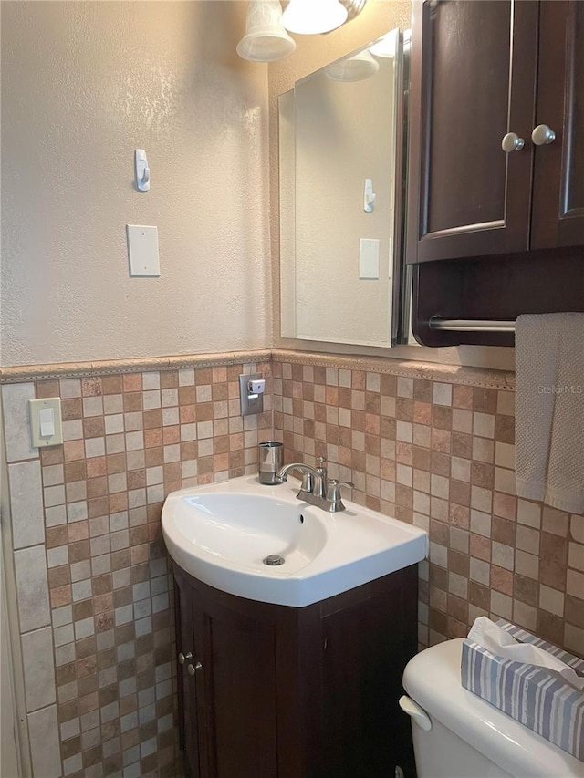 bathroom featuring vanity, toilet, and tile walls