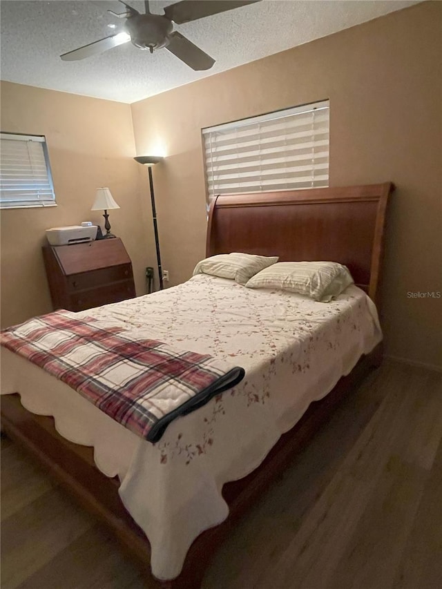 bedroom with ceiling fan, dark wood-type flooring, and a textured ceiling