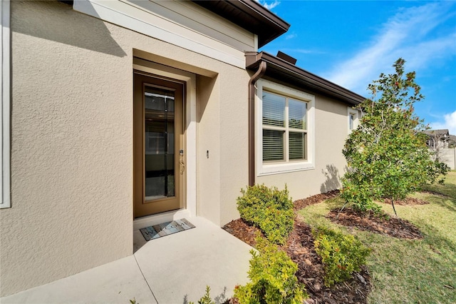 view of exterior entry with a patio and a lawn