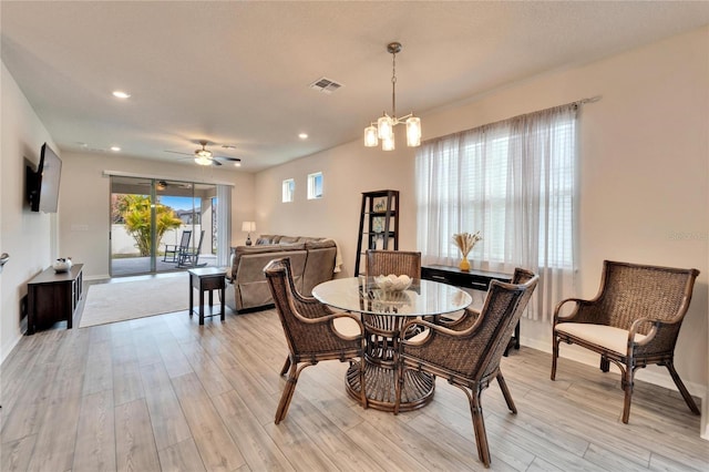 dining area featuring ceiling fan with notable chandelier and light hardwood / wood-style flooring