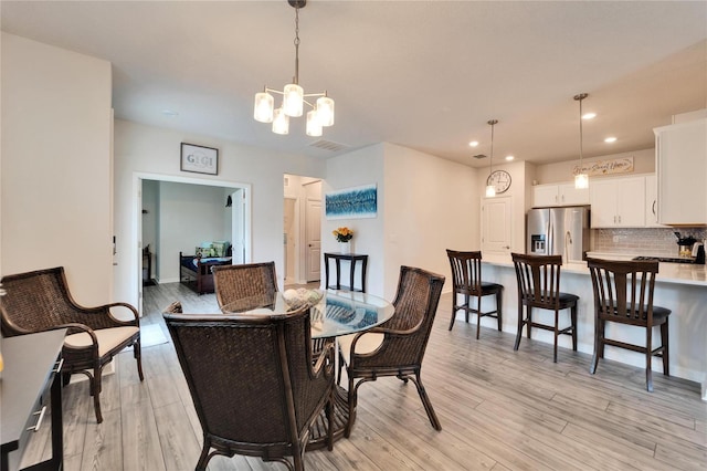 dining space with an inviting chandelier and light hardwood / wood-style flooring