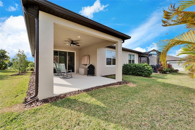 rear view of property featuring a lawn, ceiling fan, and a patio area