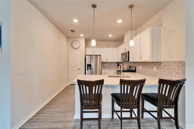 kitchen with sink, white cabinetry, backsplash, stainless steel appliances, and kitchen peninsula