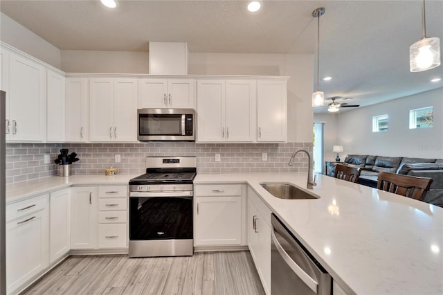 kitchen featuring white cabinetry, stainless steel appliances, sink, and hanging light fixtures