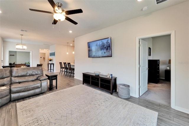 living room with baseboards, visible vents, wood finished floors, ceiling fan with notable chandelier, and recessed lighting