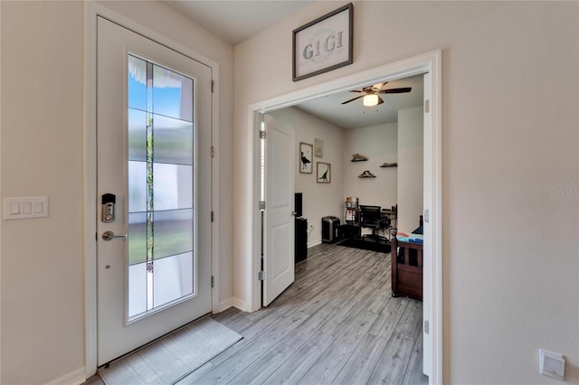 entryway with light wood-type flooring, ceiling fan, and baseboards