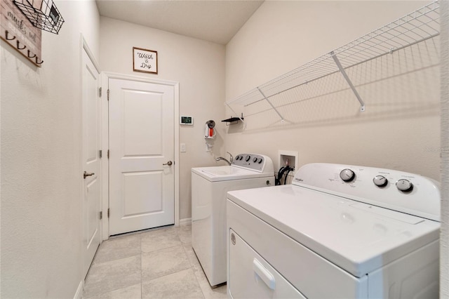 laundry area with laundry area, light tile patterned floors, baseboards, and independent washer and dryer