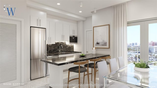 kitchen with built in fridge, a breakfast bar, tasteful backsplash, white cabinetry, and sink