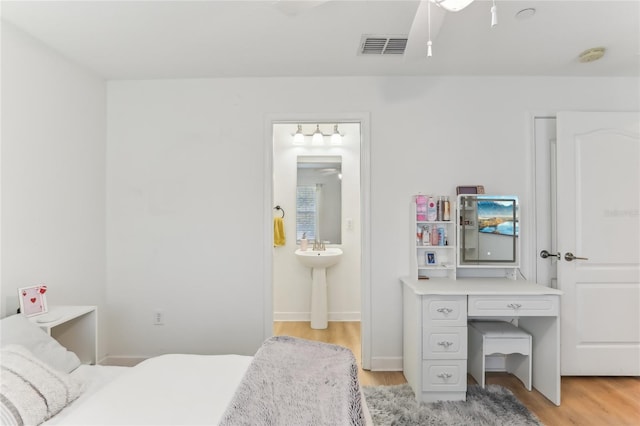 bedroom with ensuite bathroom and light hardwood / wood-style flooring