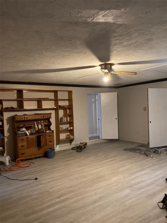 unfurnished living room with ceiling fan, wood-type flooring, ornamental molding, and a textured ceiling