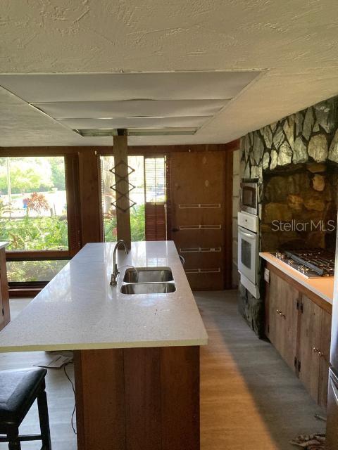 kitchen featuring sink, wood-type flooring, an island with sink, and appliances with stainless steel finishes