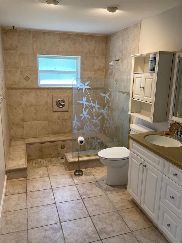 bathroom with vanity, toilet, tile patterned flooring, and a tile shower