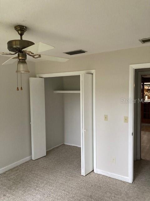 unfurnished bedroom featuring light carpet, ceiling fan, and a closet