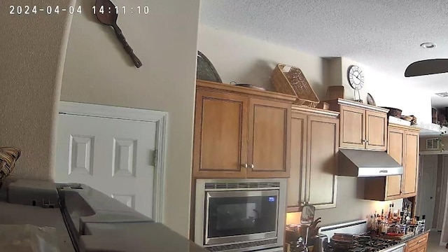 kitchen with stove, stainless steel microwave, and a textured ceiling